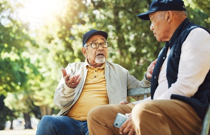male senior friends on a park bench talking about health or other serious matters. Yuri Arcurs