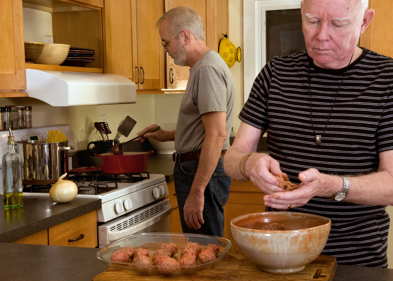 Gay couple in their modest home, fixing dinner. Finances is a long-term issue for LGBTQ+ seniors