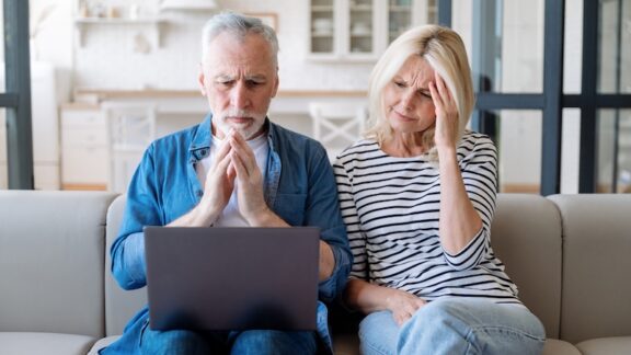 A couple on a computer making Medicare mistakes looking worried.