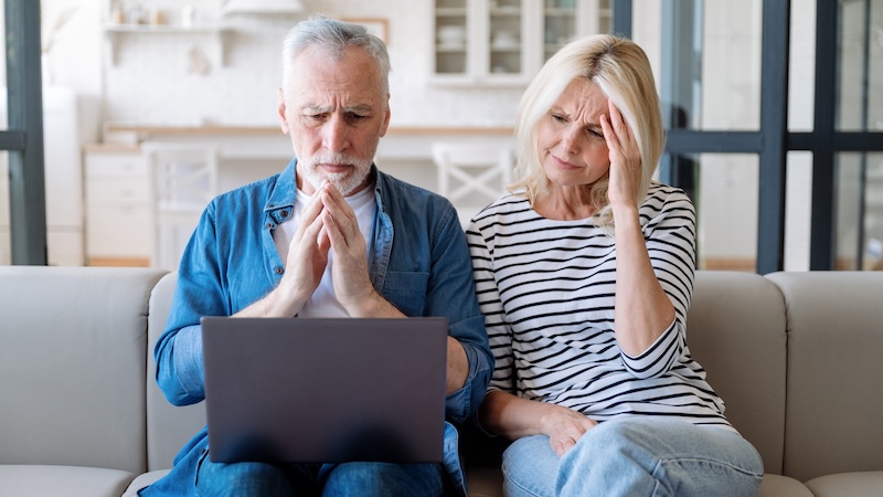 A couple on a computer making Medicare mistakes looking worried.