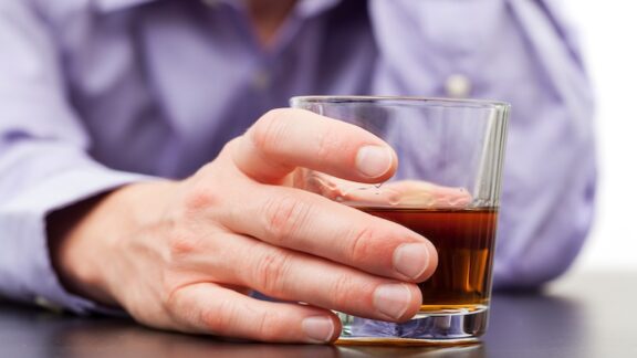 A man holding a glass of alcohol. Mayo Clinic researchers studying the connections between alcohol use and fatty liver disease found that drinking too much alcohol changes how the liver works. (Dreamstime/TCA)