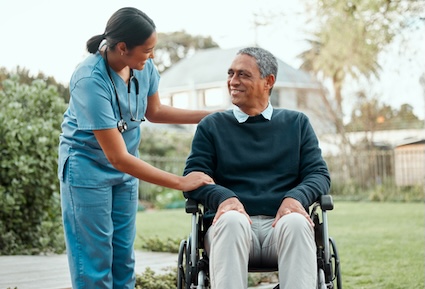 A home care nurse checks in on a patient in a wheelchair, outside his home. Yuri Arcurs