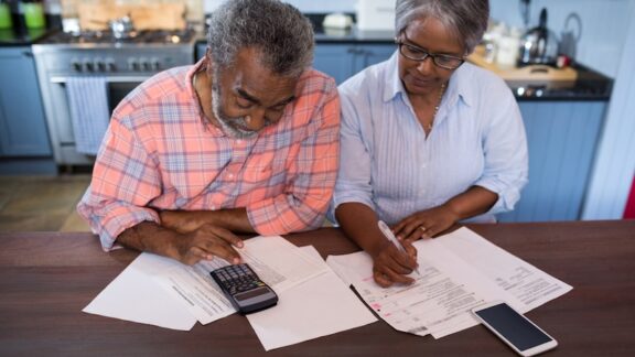 Retired couple calculating their retirement income based on Stanford’s Spend Safely in Retirement Strategy . Wavebreakmedia