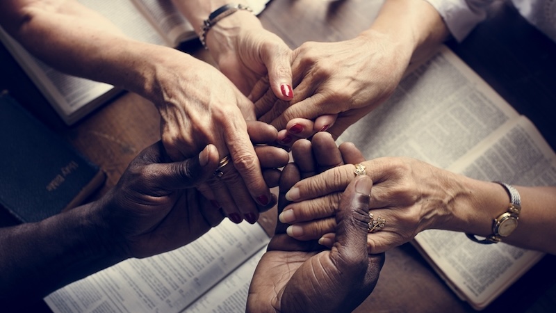 A small group of people holding hands and praying during a worship study at faith-based senior communities. Rawpixelimages