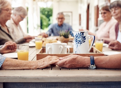 People in faith-based senior communities may say a blessing together over a meal. Yuri Arcurs