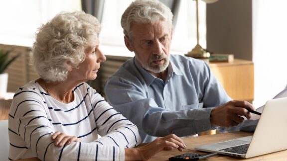 A couple on their laptop doing their finances, applying lessons from Warren Buffett. Fizkes.