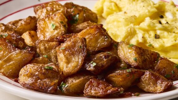 crispy breakfast potatoes next to scrambled eggs