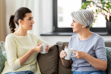 woman and her adult daughter drinking coffee or tea and having serious, end-of-life conversations. Syda Productions